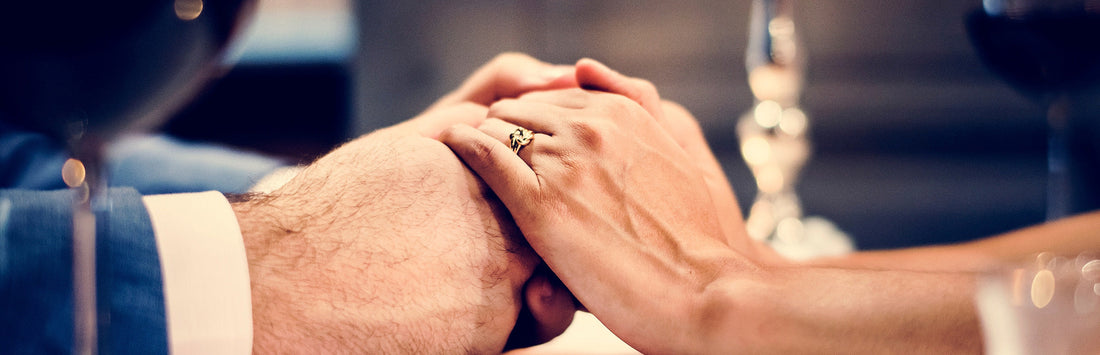 Older couple holding hands with stunning 14 karat gold ring on ring finger.