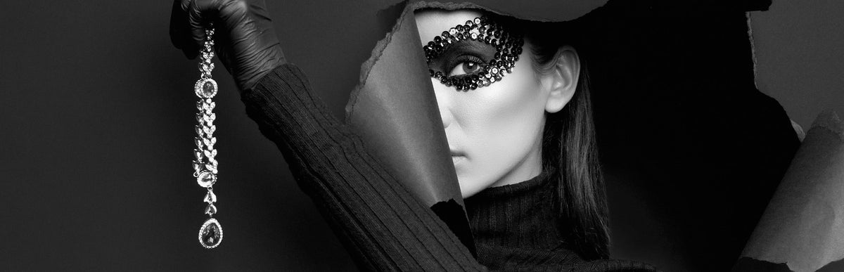 Women pearing through ripped wallpaper holding an onyx neckalce in hand and wearing a black mask over her eyes